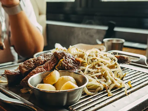 고기가 불판 위에서 숙주나물과 함께 맛있게 익는 모습